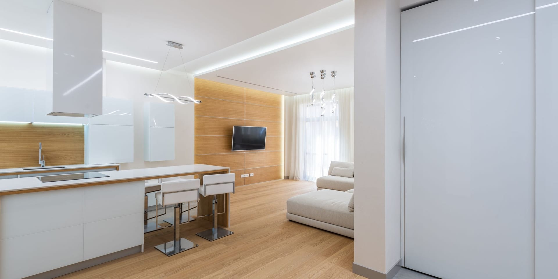 A bright open-plan kitchen and living room with clear counters and polished wood floors